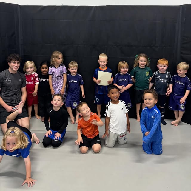 The Little Ninjas class of pre school children posing on the mats with their coach.