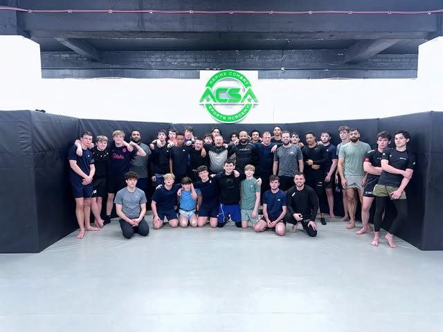 The full academy squad lined up in front of the cage.
